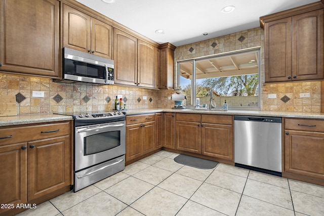 kitchen with light tile patterned floors, decorative backsplash, stainless steel appliances, and a sink