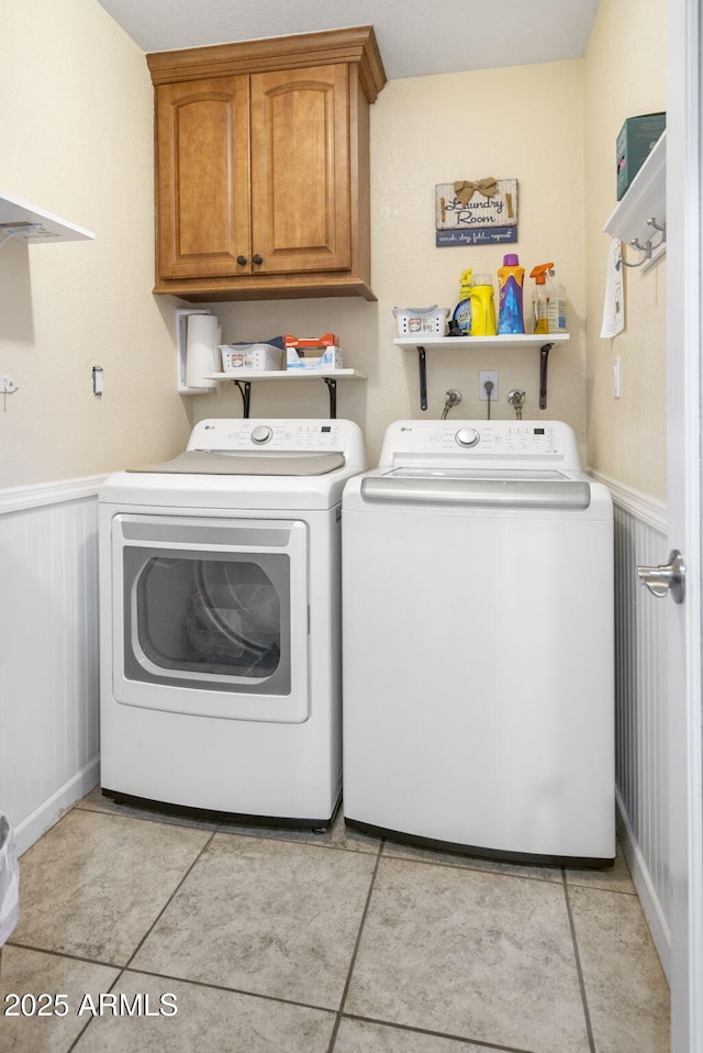 washroom with cabinet space, a wainscoted wall, and washer and dryer