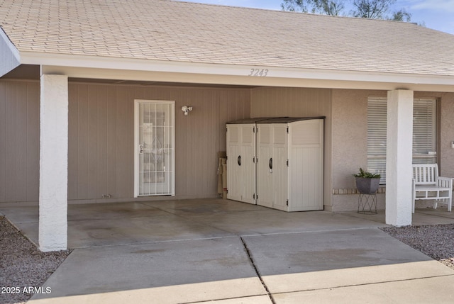 doorway to property featuring an attached carport and concrete driveway