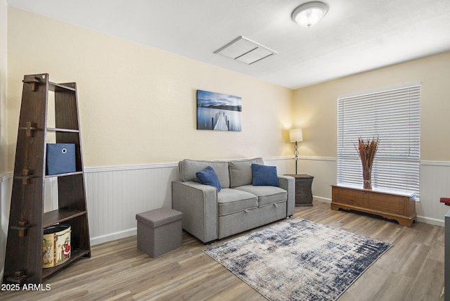 living area featuring a wainscoted wall and wood finished floors