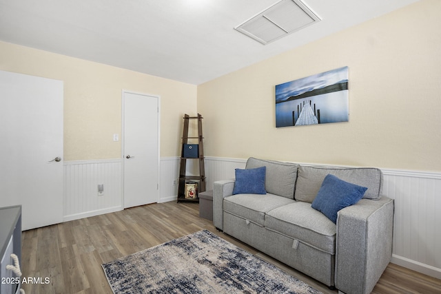 living room with visible vents, wood finished floors, and wainscoting