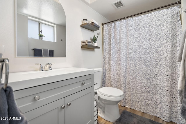 full bath with vanity, toilet, wood finished floors, and visible vents