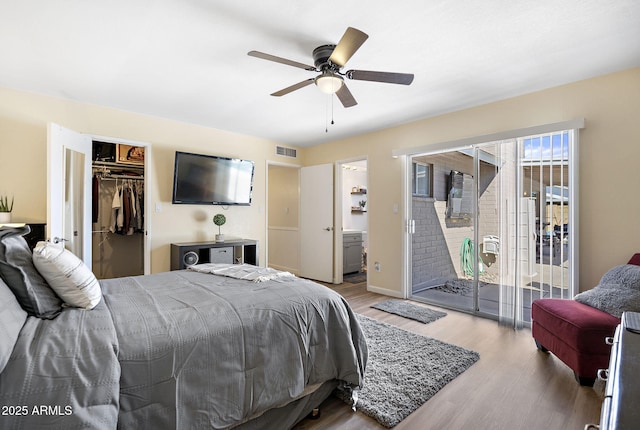 bedroom featuring visible vents, access to outside, wood finished floors, a closet, and a spacious closet