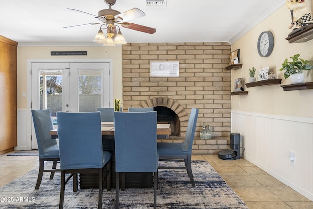 dining space featuring ceiling fan, ornamental molding, wainscoting, and light tile patterned floors