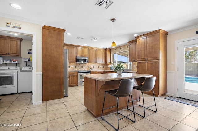 kitchen featuring light tile patterned floors, visible vents, appliances with stainless steel finishes, crown molding, and washer and clothes dryer