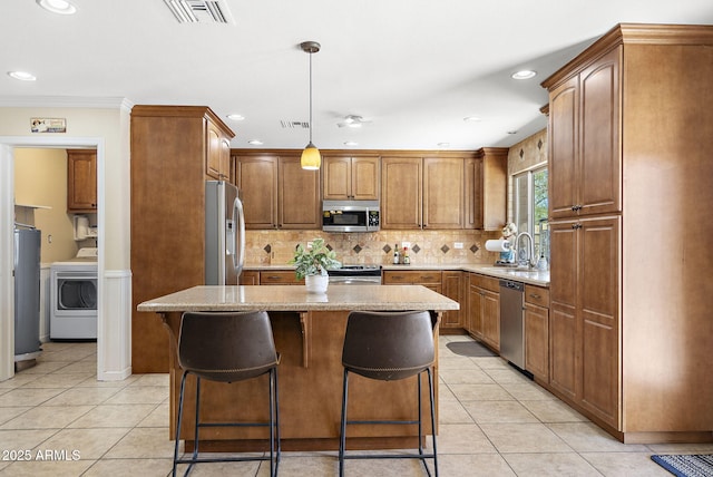 kitchen featuring visible vents, water heater, stainless steel appliances, decorative backsplash, and washer / dryer