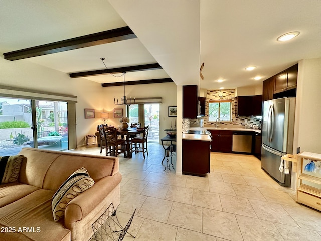 kitchen featuring a healthy amount of sunlight, stainless steel appliances, beam ceiling, and decorative backsplash