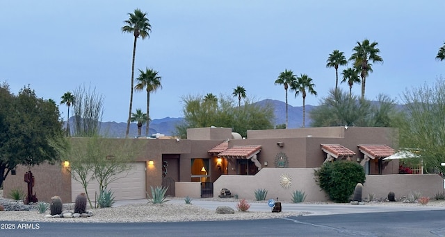 pueblo revival-style home with a garage and a mountain view