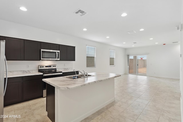 kitchen featuring recessed lighting, appliances with stainless steel finishes, open floor plan, a sink, and an island with sink