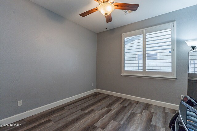 empty room featuring ceiling fan, plenty of natural light, and dark wood-type flooring