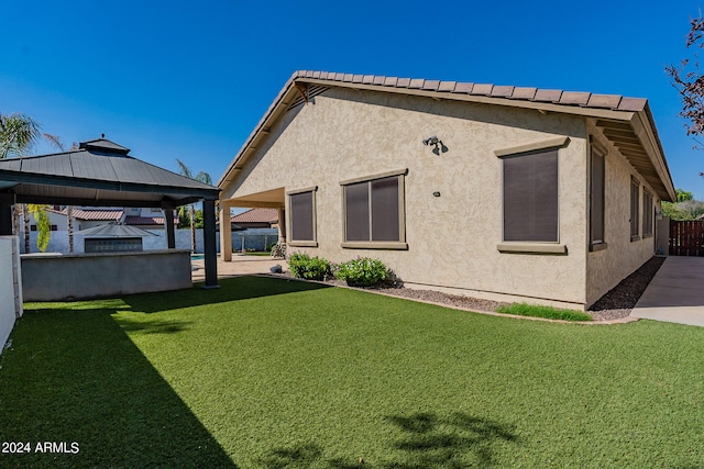 back of property with a gazebo, a patio, and a lawn