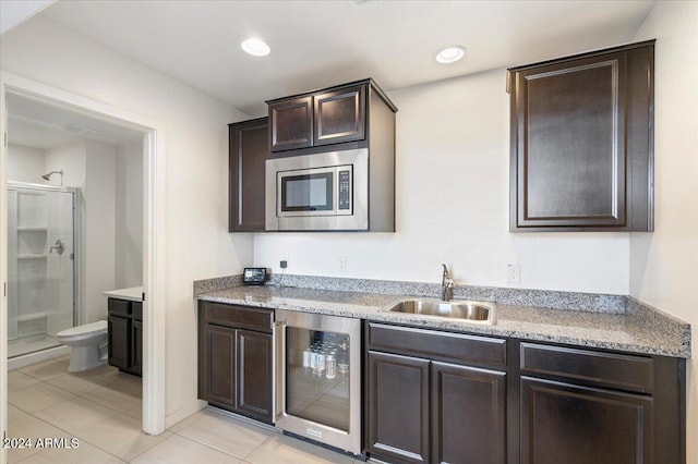 kitchen with light tile patterned floors, stainless steel microwave, dark brown cabinets, and beverage cooler