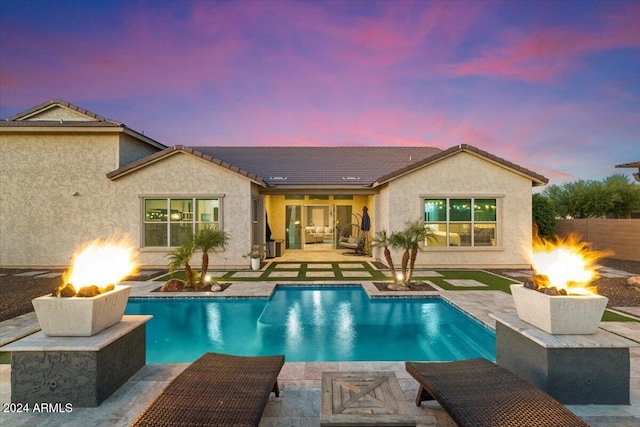 back house at dusk with a patio area and an outdoor living space with a fire pit