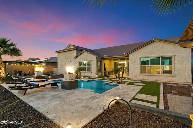 pool at dusk featuring a patio