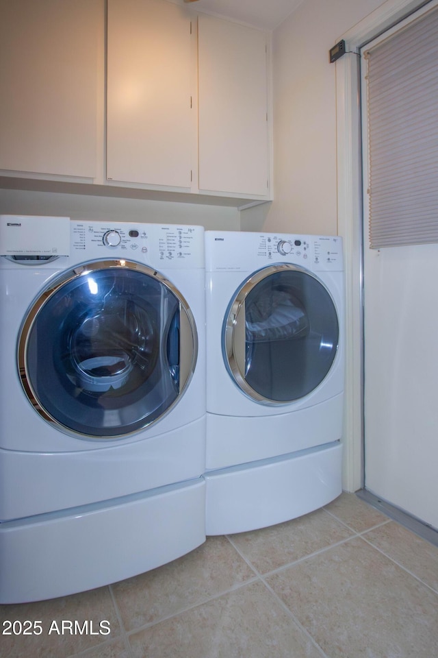 laundry room featuring cabinets, light tile patterned floors, and washing machine and clothes dryer