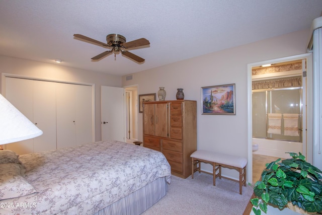 carpeted bedroom with ceiling fan, ensuite bath, a closet, and a textured ceiling