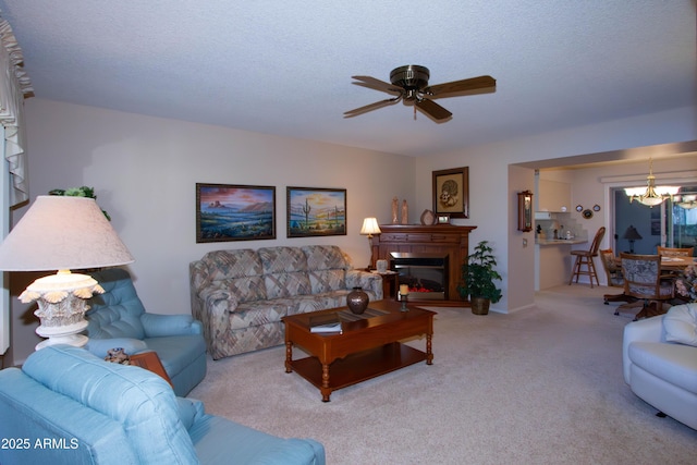 living room featuring ceiling fan with notable chandelier, a textured ceiling, and carpet flooring