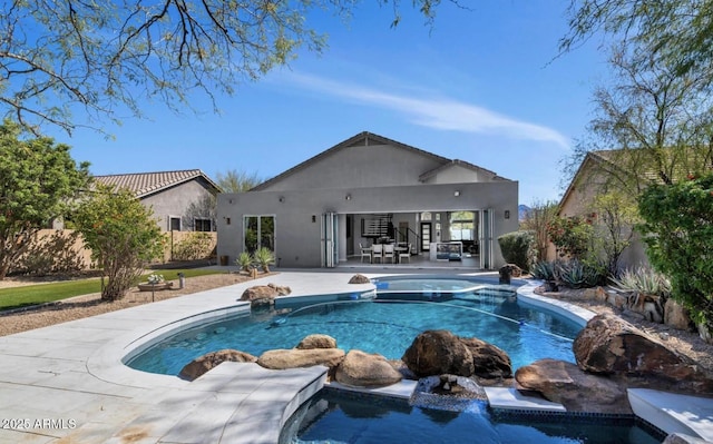 outdoor pool with an in ground hot tub and a patio area