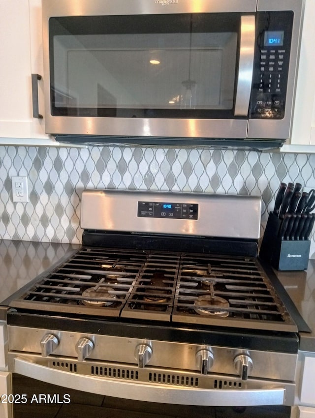 interior space with white cabinets, stainless steel appliances, and decorative backsplash