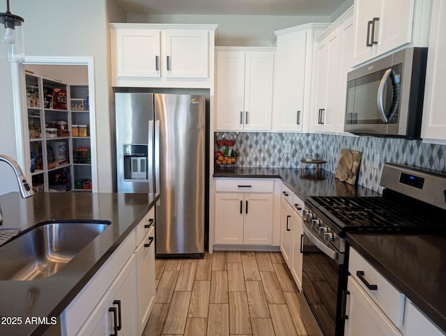 kitchen featuring sink, white cabinetry, tasteful backsplash, light hardwood / wood-style flooring, and appliances with stainless steel finishes