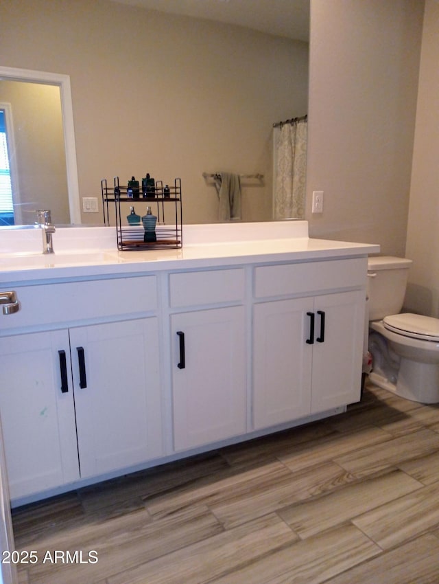 bathroom with toilet, vanity, hardwood / wood-style flooring, and curtained shower