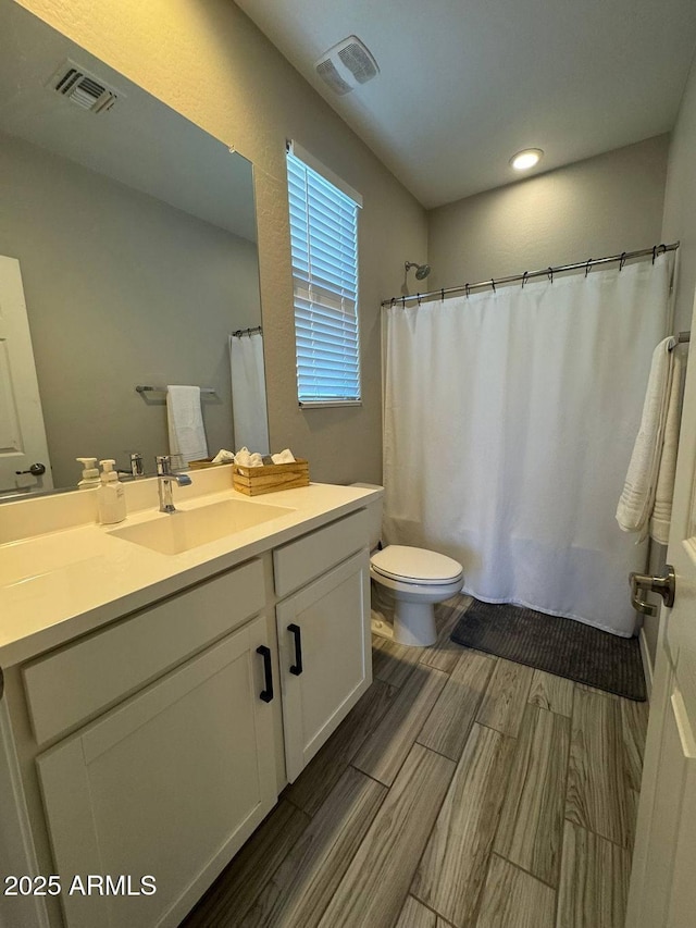 bathroom featuring walk in shower, vanity, and toilet