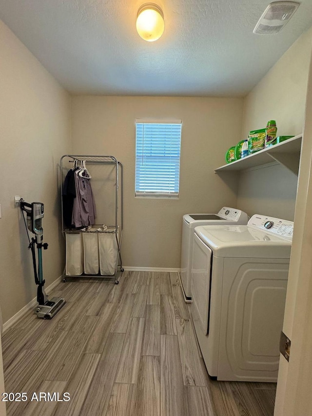 clothes washing area with light hardwood / wood-style flooring and independent washer and dryer