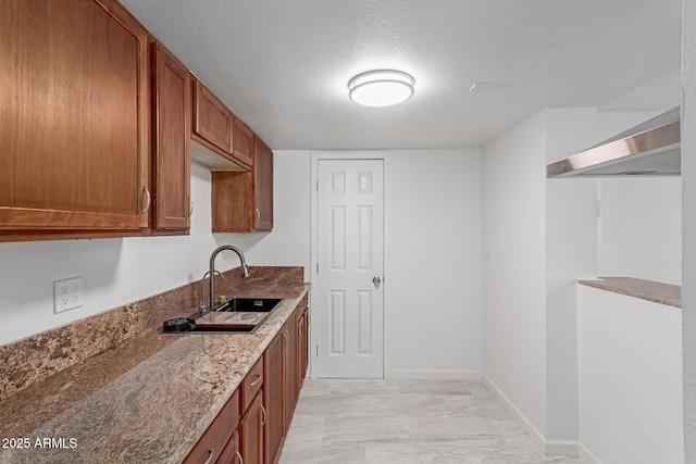 kitchen featuring sink, light stone counters, and a textured ceiling