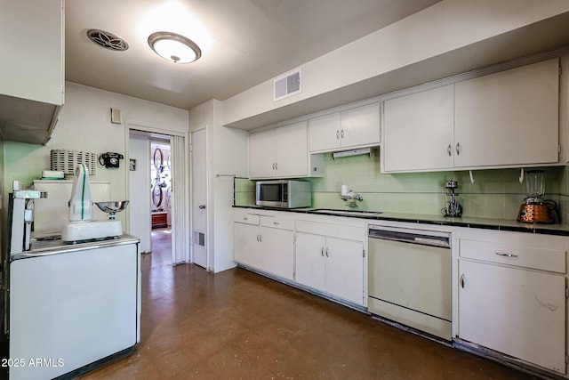 kitchen featuring white dishwasher, stainless steel microwave, a sink, and backsplash