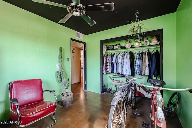 living area with a ceiling fan and concrete flooring