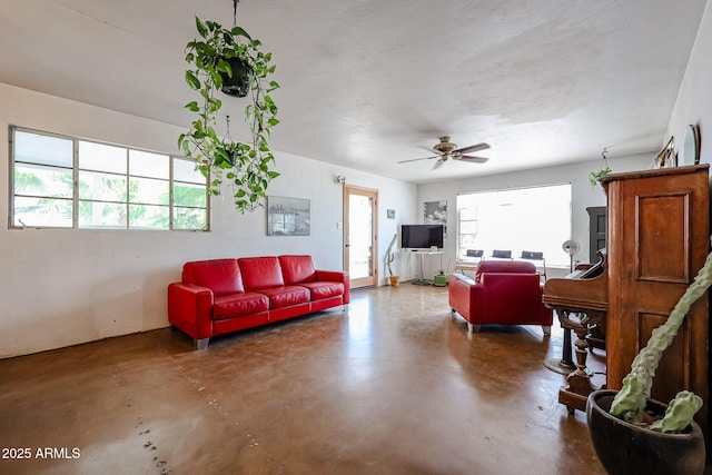 living room featuring concrete flooring and a ceiling fan