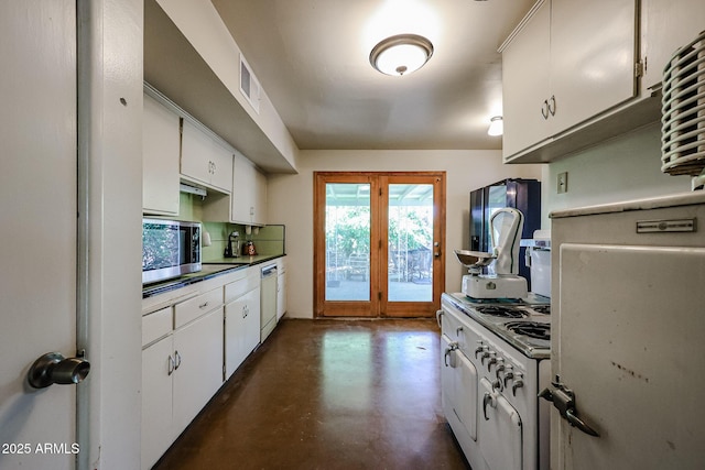 kitchen with appliances with stainless steel finishes, white cabinets, finished concrete floors, and dark countertops