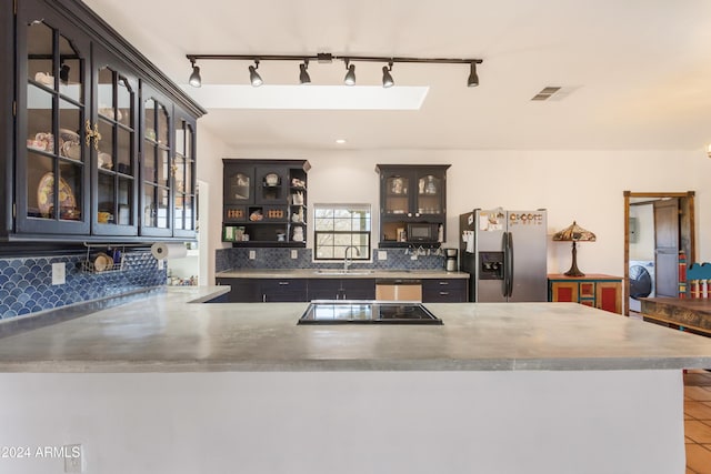 kitchen with sink, tasteful backsplash, kitchen peninsula, washer / clothes dryer, and black appliances