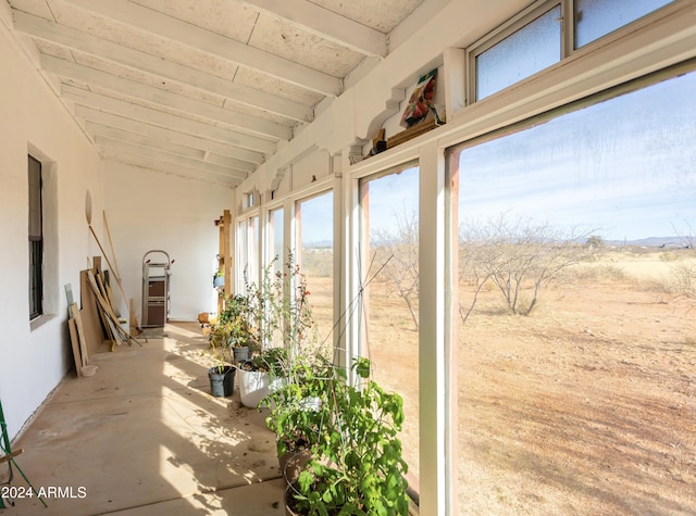 unfurnished sunroom featuring vaulted ceiling with beams