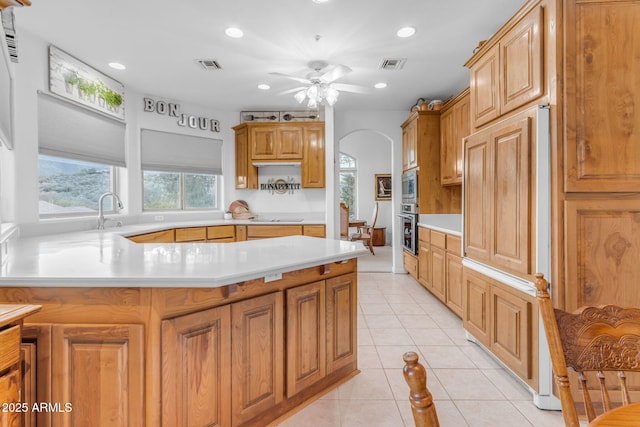 kitchen with ceiling fan, black electric stovetop, oven, kitchen peninsula, and light tile patterned flooring