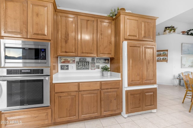 kitchen featuring light tile patterned floors, vaulted ceiling, and stainless steel appliances