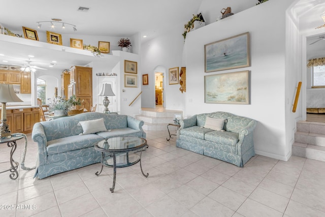 living room featuring ceiling fan, light tile patterned floors, and a towering ceiling