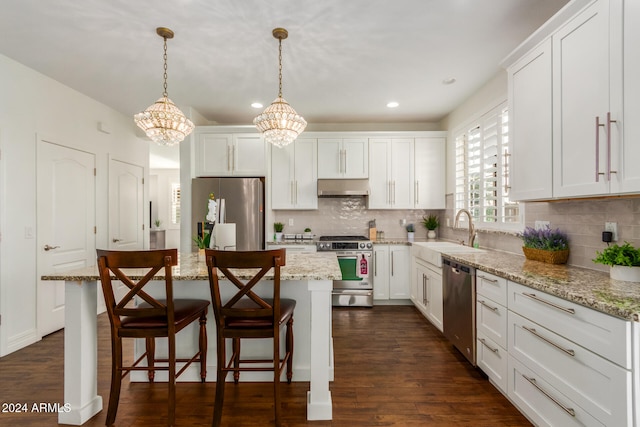 kitchen with appliances with stainless steel finishes, a kitchen island, pendant lighting, and sink