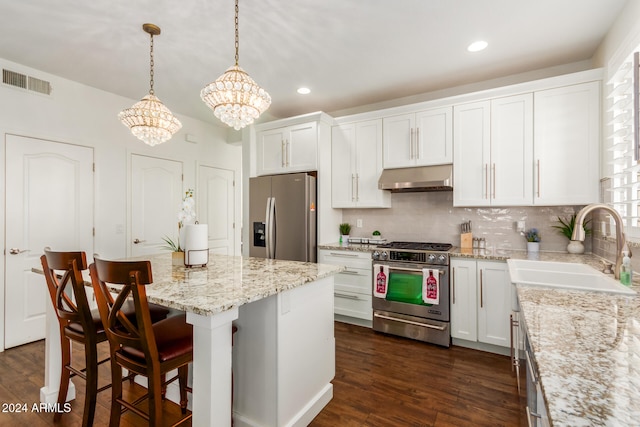 kitchen featuring stainless steel appliances, dark wood-type flooring, decorative light fixtures, white cabinetry, and range hood