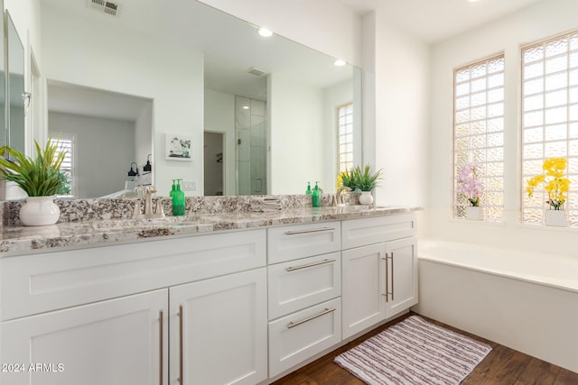 bathroom with vanity, hardwood / wood-style floors, and plus walk in shower