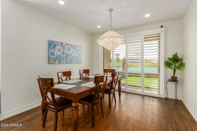 dining area featuring dark wood-type flooring and an inviting chandelier