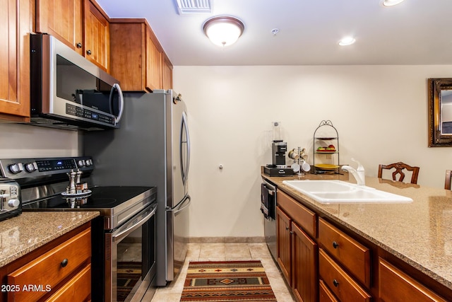 kitchen with light stone countertops, appliances with stainless steel finishes, and sink