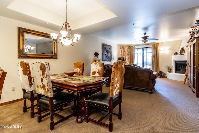 carpeted dining room with a raised ceiling and ceiling fan with notable chandelier