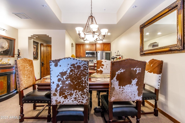 dining room featuring a raised ceiling, a chandelier, and carpet