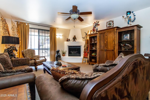 carpeted living room with a large fireplace and ceiling fan