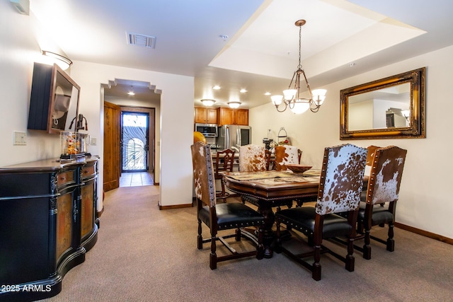 carpeted dining space with a raised ceiling