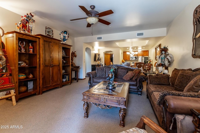 carpeted living room featuring ceiling fan with notable chandelier