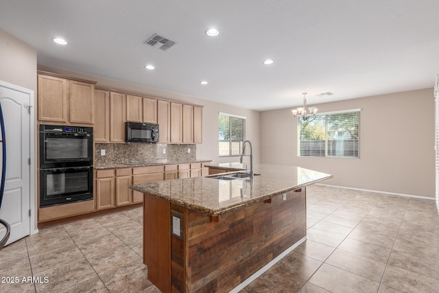 kitchen featuring sink, black appliances, an island with sink, light stone countertops, and backsplash