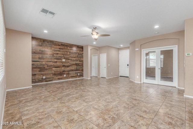 empty room with wooden walls, french doors, and ceiling fan