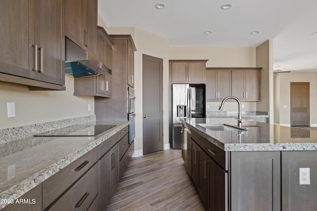 kitchen with an island with sink, light hardwood / wood-style flooring, sink, and appliances with stainless steel finishes